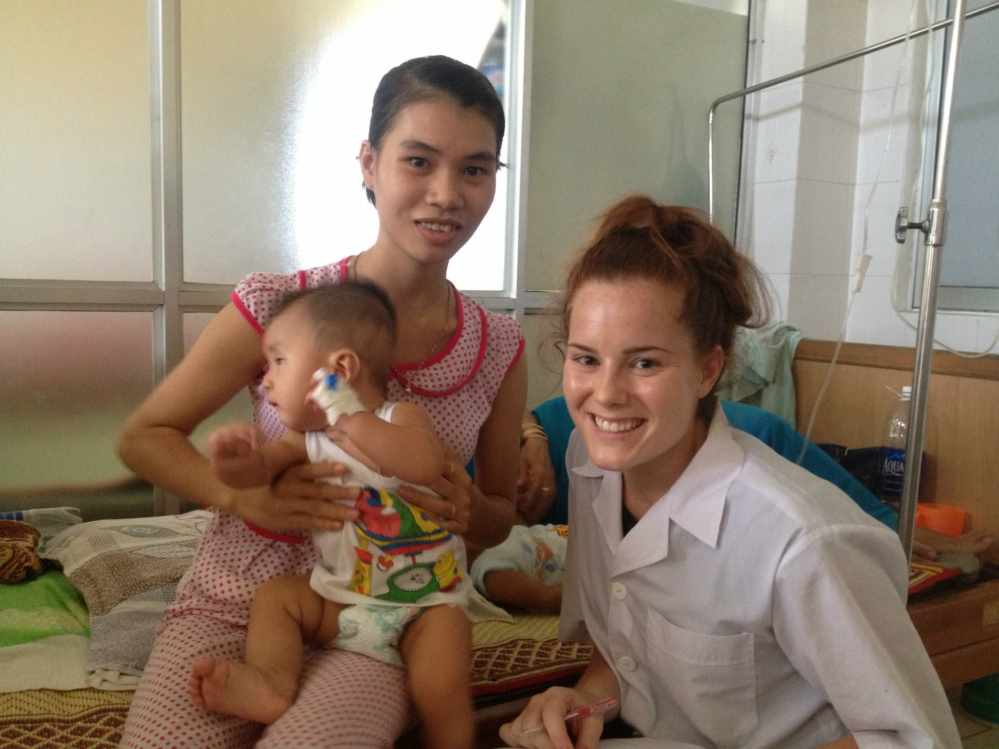 Burke smiles with a mother and her child at the pediatric ward in Hue University Hospital after an interview